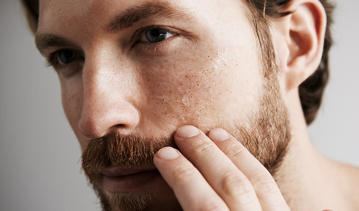 Mann berührt seinen Bart mit der Hand